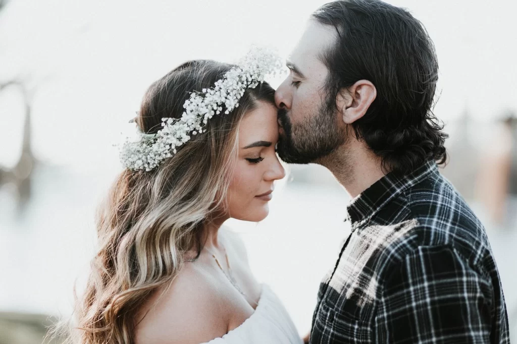 man kissing woman on forehead
