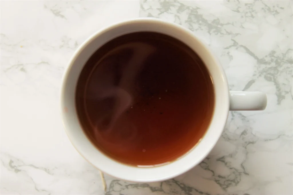 dark brown herbal tea in white teacup