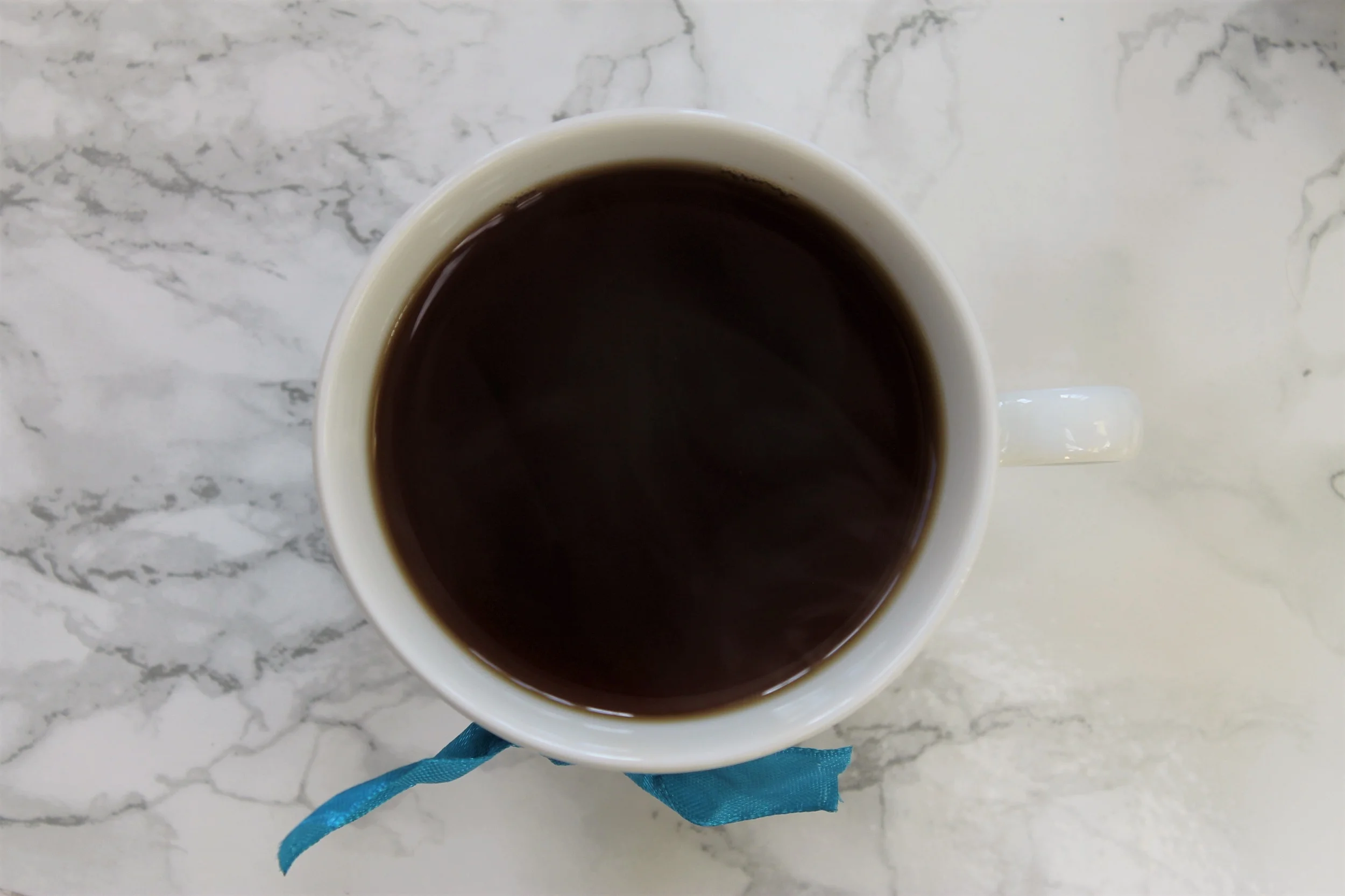 black tea in white tea cup with blue ribbon
