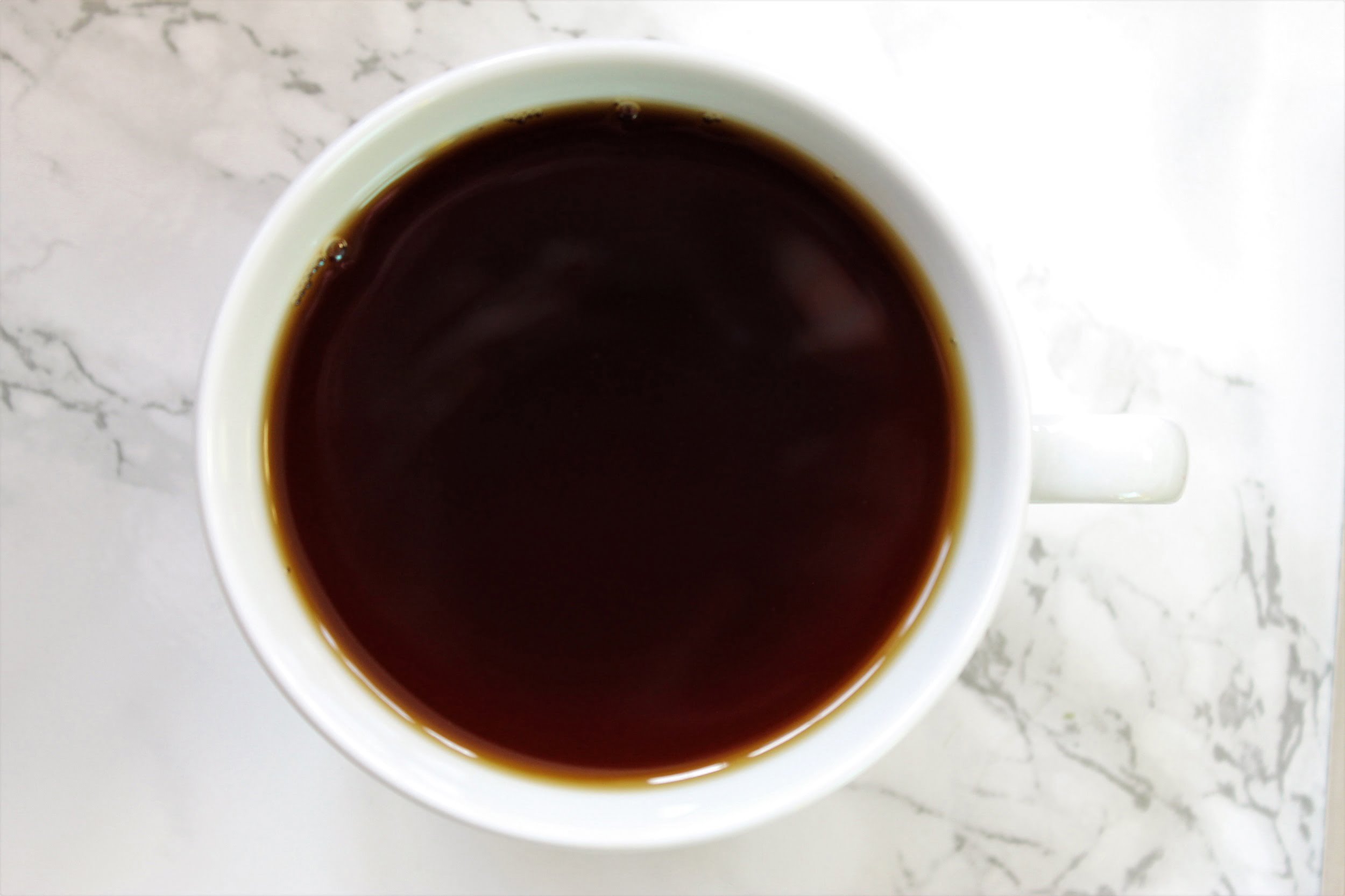 black brown tea in white teacup on marble