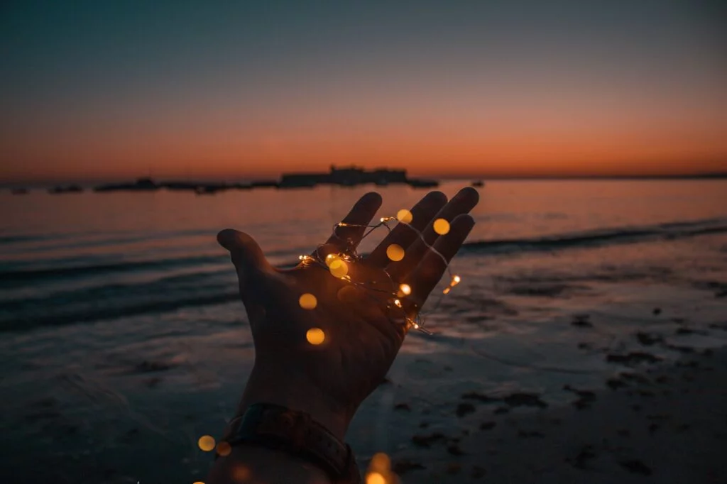 dream hand reaching out across water at dusk