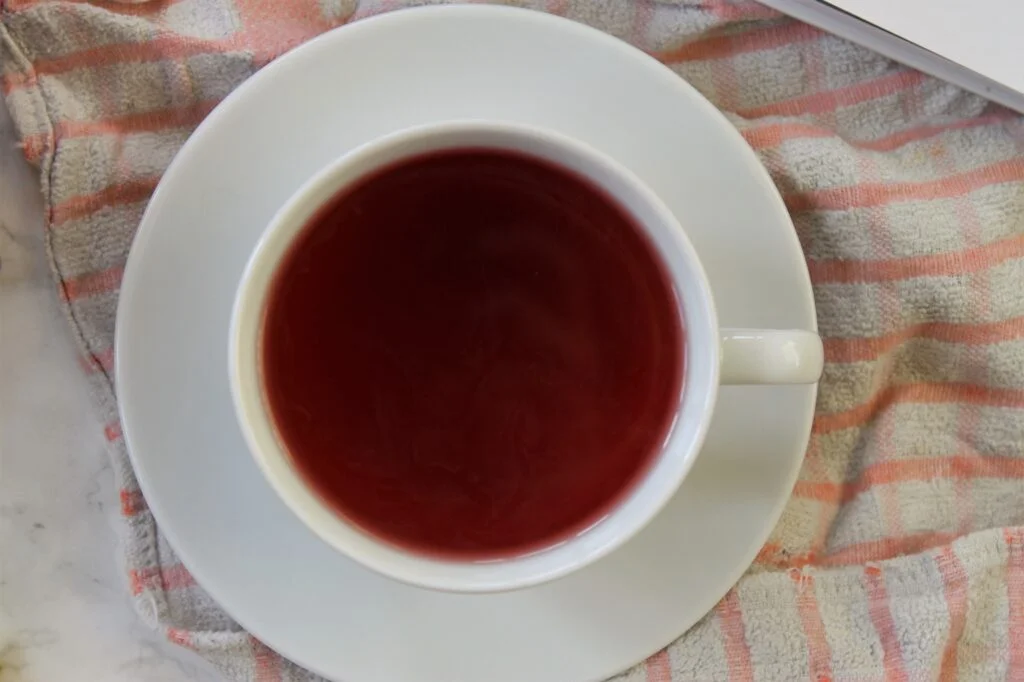 red fruit tea in a white teacup