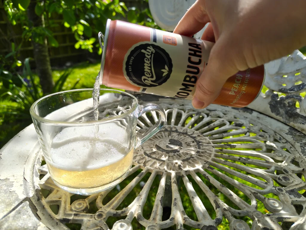 pouring fizzy kombucha into glass cup